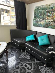 a black leather couch with blue pillows in a living room at Apartamento cerca al centro y sitios turísticos in Bogotá