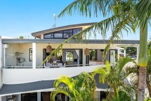 a large white house with palm trees in front of it at Sophie's Place ReLaunch - Luxury Penthouse in Byron Bay