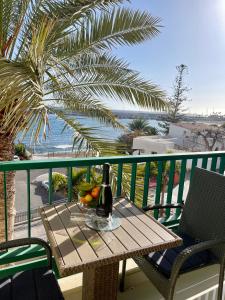 un tavolo con una bottiglia di vino e frutta sul balcone di Royal View Apartment - Los Cristianos a Los Cristianos