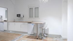 a kitchen with white cabinets and a table and a stool at Cortijo EL CHAMAN LOS ESCULLOS in Almería