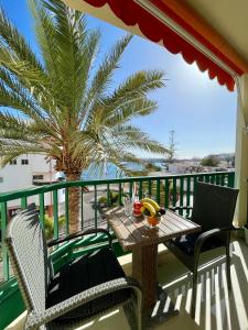 a table and chairs on a balcony with a palm tree at Royal View Apartment - Los Cristianos in Los Cristianos