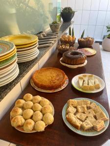 uma mesa com tortas e doces e pratos de comida em Pousada Sol e Mar em Morro de São Paulo