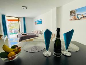 un tavolo con una bottiglia di vino e un cesto di frutta di Royal View Apartment - Los Cristianos a Los Cristianos