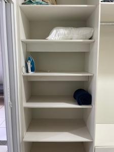 a closet with white shelves and a pillow at Ap completo otimo Local próximo Shopping 3 in Campo Grande