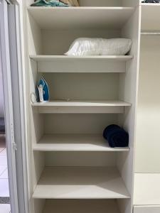 a closet with white shelves and a pillow at Apto 3 otimo Local próximo Shopping in Campo Grande