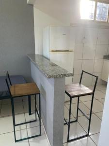 a kitchen with two chairs and a counter and a refrigerator at Ap completo otimo Local próximo Shopping 3 in Campo Grande