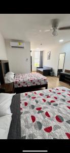 1 dormitorio con 2 camas y colcha con rosas rojas en Hotel del Alba Inn & Suites, en Aguascalientes