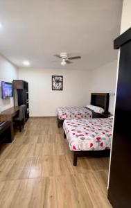 a room with two beds and a desk and a table at Hotel del Alba Inn & Suites in Aguascalientes