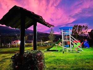 a group of children playing on playground equipment in a field at Casa de campo con hermosa vista in Riobamba