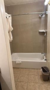 Deluxe Inn Of Roswell في روزويل: حمام مع حوض استحمام أبيض ومرحاض
