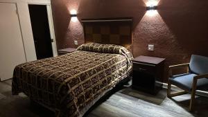 Deluxe Inn Of Roswell في روزويل: غرفه فندقيه بسرير وكرسي