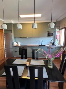 uma cozinha com uma mesa preta e cadeiras e uma cozinha com um balcão em aerOPOrto Guesthouse em Maia
