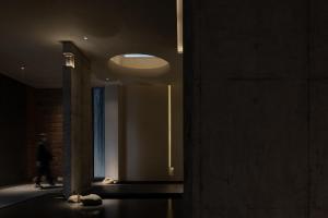 una persona che cammina attraverso un corridoio buio con una luce di Phoenix Hall House Hotel a Fenghuang