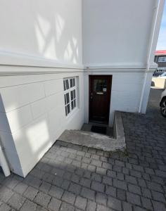a white building with a door and a brick sidewalk at Reykjavik Urban Escape 2-Bedroom Haven with Private Entrance in Reykjavík