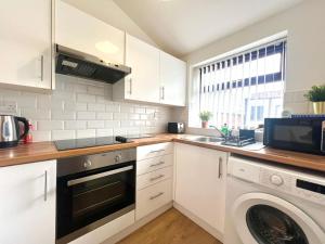 cocina con armarios blancos, lavadora y secadora en Quaint 2Bed House near Wigan Centre en Ince-in-Makerfield