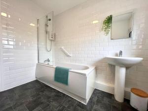 y baño blanco con lavabo, bañera y lavamanos. en Quaint 2Bed House near Wigan Centre en Ince-in-Makerfield