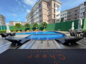 a swimming pool with tables and chairs in front of a building at MJC's Stay and Relax in Marilao