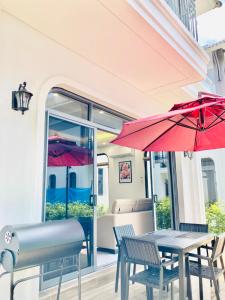 - une table et des chaises avec un parasol rouge sur la terrasse dans l'établissement V3E02 Dahlia villa - khu nghỉ dưỡng Sonasea Vân Đồn, à Cái Rồng