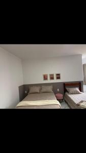 sypialnia z 2 łóżkami i 2 zdjęciami na ścianie w obiekcie Viçosa Flat w mieście Viçosa do Ceará