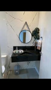 uma casa de banho com um lavatório e um espelho na parede em Viçosa Flat em Viçosa do Ceará