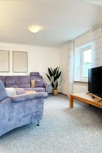 a living room with a blue couch and a tv at Charmantes und ruhiges Ferienhaus - Strandnah und ideal für große Gruppen - mit Fahrradunterstellplatz und Parkplatz in Scharbeutz