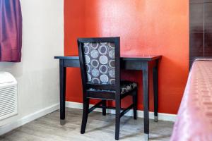 uma cadeira preta sentada numa secretária com uma parede laranja em Bell Manor Motel em Bell