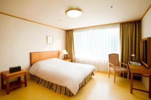 una camera d'albergo con letto, scrivania e finestra di Wellihilli Park Resort a Hoengsong