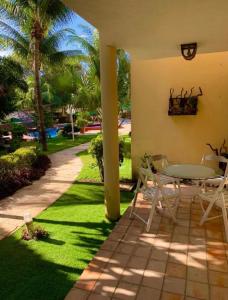 a patio with a table and chairs on the grass at Solar de Pipa Elegance Flat - Frente Piscina in Pipa