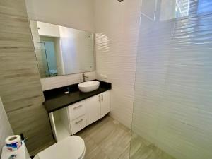 y baño con lavabo, espejo y aseo. en cozy apartment near the beach los corales punta Cana., en Punta Cana