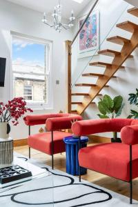 una sala de estar con sillas rojas y una escalera en Vibrant Urban Escape, Family Friendly - Sleeps 8!, en Londres