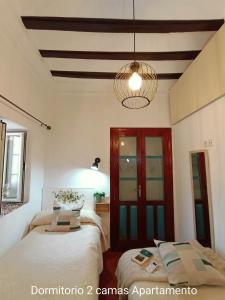 um quarto com 2 camas e um lustre em El Detalle em Zahara de la Sierra