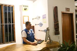 a man standing at a desk with a laptop computer at Cruz Roja - Turismo Solimões in Leticia
