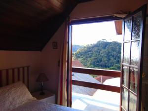 a bedroom with a bed and a large window at Pousada Refúgio Akatu in Campos do Jordão