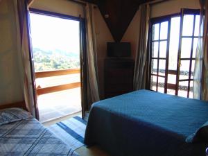 um quarto com uma cama e uma grande janela em Pousada Refúgio Akatu em Campos do Jordão