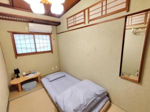 a small bedroom with a bed and a table at Hostel Caranashi in Osaka