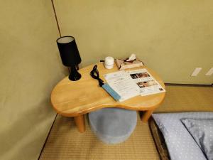 a small wooden table in a room with a bed at Hostel Caranashi in Osaka