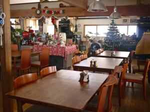 乗鞍高原の宿テンガロンハットB&BTengallonhat في ماتسوموتو: مطعم بطاولات وكراسي وشجرة عيد الميلاد
