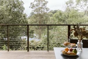 two plates of fruit on a table on a balcony at Kookaburra Cottage at On Burgum Pond in Maleny