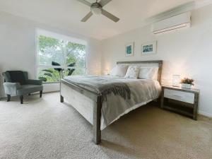 a bedroom with a bed and a chair and a window at Kookaburra 2-Bedroom at On Burgum Pond Cottages in Maleny