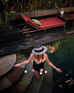 a woman in a hat standing in a swimming pool at Cambana Residence in Siem Reap