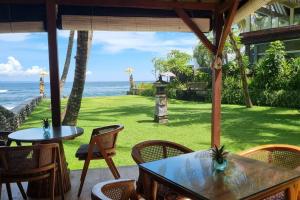 a patio with tables and chairs and the ocean at Apartment Nine at the Bayshore Resort Candidasa in Candidasa