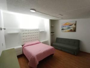 - une chambre avec un lit rose et un canapé dans l'établissement Loft Santa Rosa, à Apizaco