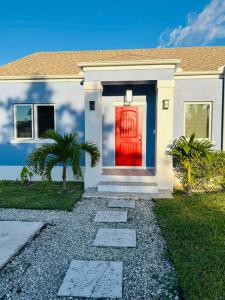 una casa con una puerta roja y palmeras en Ruby’s Place en Nassau