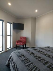 a bedroom with a bed and a red chair at Stay and Play Golf in Worrolong