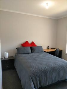 Worrolong的住宿－Stay and Play Golf，一间卧室配有一张带红色枕头的床和一张书桌