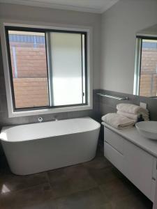 a bathroom with a large white tub and a sink at Stay and Play Golf in Worrolong