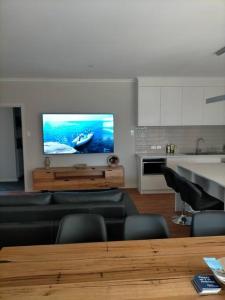 a living room with a couch and a tv on a wall at Stay and Play Golf in Worrolong
