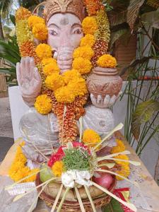 una statua di una testa con dei fiori sul tavolo di Ganesh Lodge a Candidasa