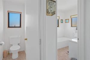 a white bathroom with a toilet and a sink at The Barn Cabins & Camp in Marahau