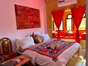 1 dormitorio con 1 cama grande y cortinas rojas en Hotel Murad Haveli Jaisalmer, en Jaisalmer